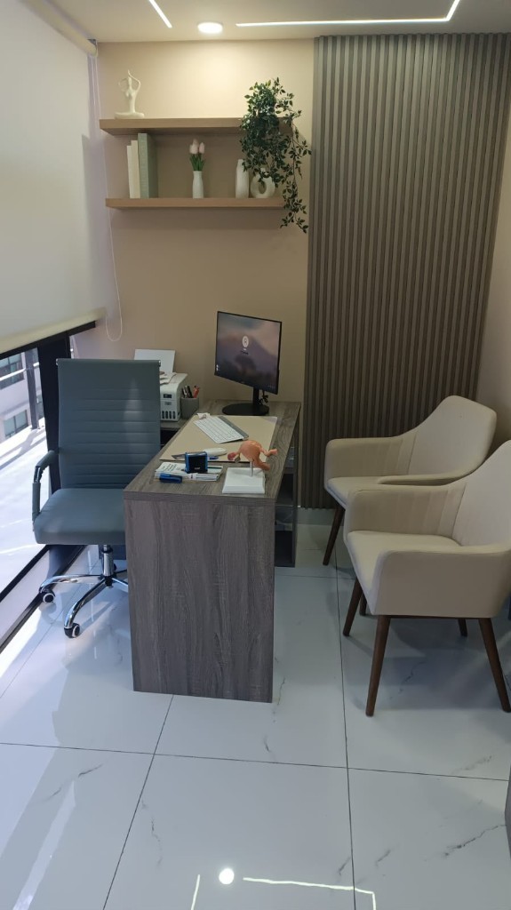 Consultorio de Atria, con escritorio, silla del médico y dos sillones para pacientes.