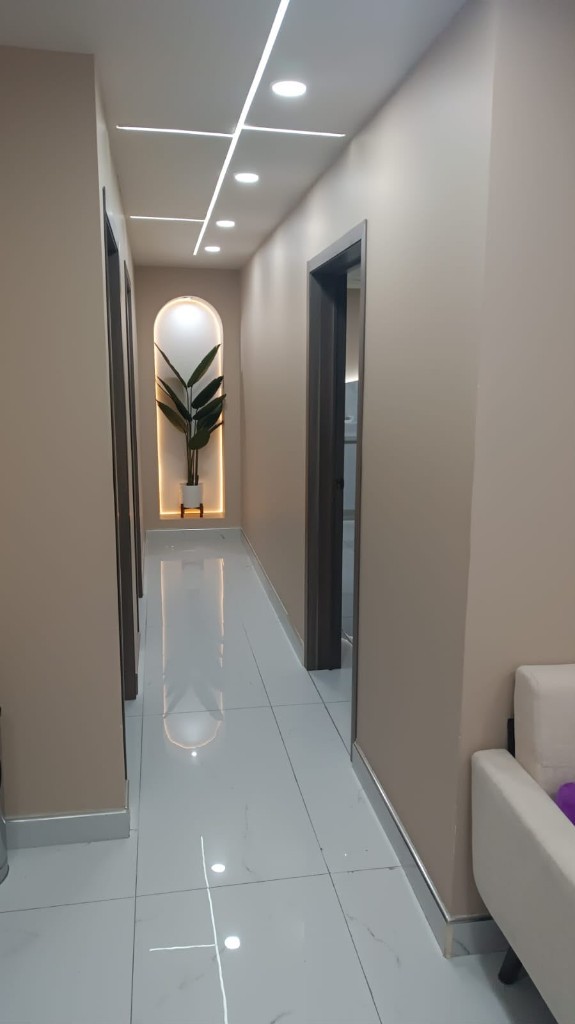 Pasillo de Atria Women Care, con muros beige y un nicho iluminado con una planta.